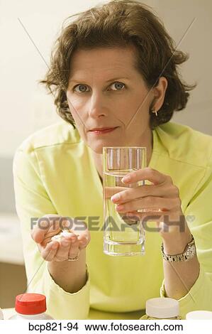 Picture - Woman holding vitamins and supplements. Fotosearch