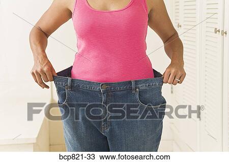 Woman in big pants showing off weight loss View Large Photo Image Stock Image - Woman in big pants showing off weight loss. Fotosearch