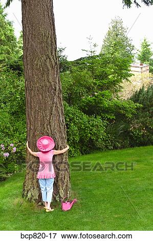 Stock Photo - Woman in festive pink hat hugging tree. Fotosearch