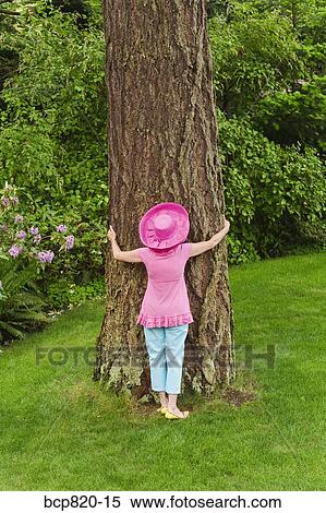 Stock Photography - Woman in festive pink hat hugging tree. Fotosearch