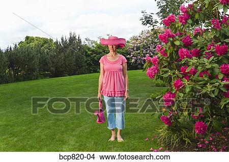 Woman in festive pink hat standing in garden View Large Photo Image Picture - Woman in festive pink hat standing in garden. Fotosearch