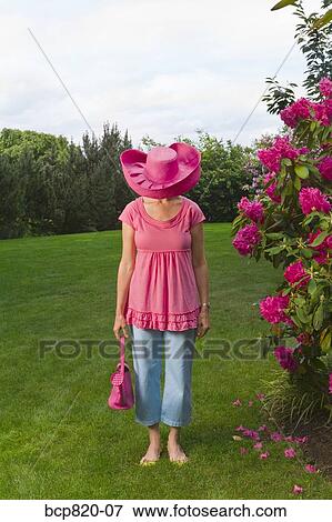 Stock Photo - Woman in festive pink hat standing in garden. Fotosearch