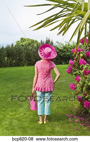 Woman in festive pink hat standing in garden View Large Photo Image Stock Photo - Woman in festive pink hat standing in garden. Fotosearch