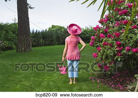 Stock Photo - Woman in festive pink hat standing in garden. Fotosearch