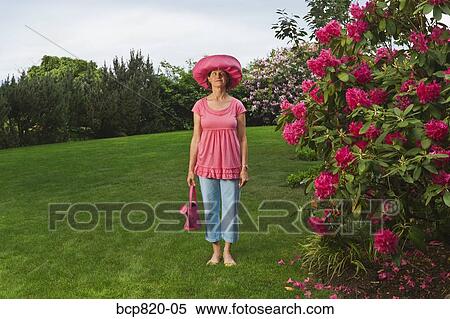 Woman in festive pink hat standing in garden View Large Photo Image Stock Photography - Woman in festive pink hat standing in garden. Fotosearch