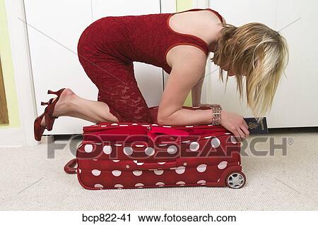 Woman in red dress kneeling on polka dot patterned suitcase View Large Photo Image Stock Image - Woman in red dress kneeling on polka dot patterned suitcase. Fotosearch