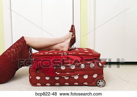 Woman in red dress resting on polka dot patterned suitcase View Large Photo Image Stock Photo - Woman in red dress resting on polka dot patterned suitcase. Fotosearch