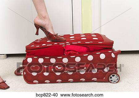 Woman in red shoes stepping on polka dot patterned suitcase View Large Photo Image Stock Image - Woman in red shoes stepping on polka dot patterned suitcase. Fotosearch