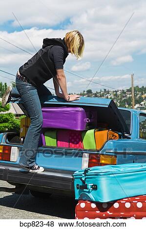Woman loading car trunk with colorful suitcases View Large Photo Image Stock Photo - Woman loading car trunk with colorful suitcases. Fotosearch