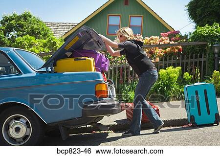 Woman loading car trunk with colorful suitcases View Large Photo Image Stock Photograph - Woman loading car trunk with colorful suitcases. Fotosearch