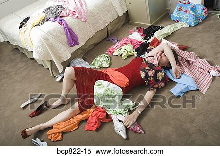 Woman on bedroom floor buried under clothing View Large Photo Image Stock Photography - Woman on bedroom floor buried under clothing. Fotosearch