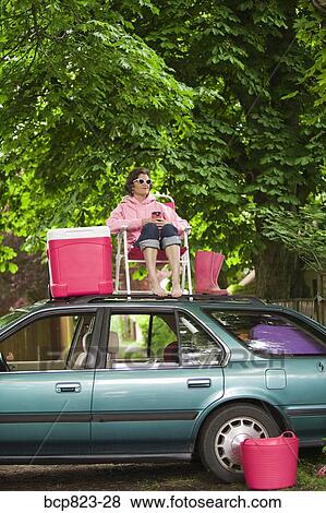 Woman picnicking on top of car View Large Photo Image Stock Photo - Woman picnicking on top of car. Fotosearch