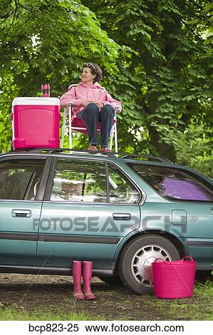 Stock Photography - Woman picnicking on top of car. Fotosearch