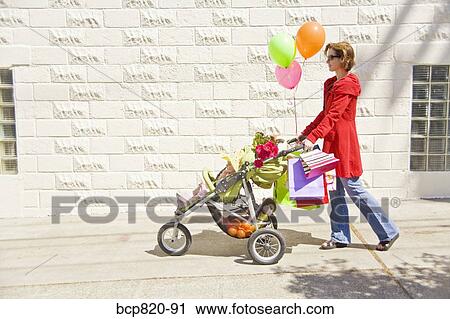Stock Image - Woman pushing baby girl in stroller. Fotosearch