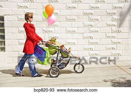 Woman pushing baby girl in stroller View Large Photo Image Stock Image - Woman pushing baby girl in stroller. Fotosearch