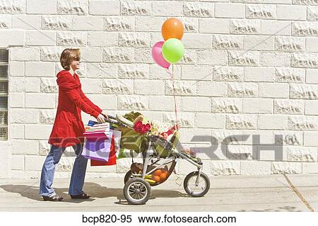 Stock Photography - Woman pushing baby girl in stroller. Fotosearch