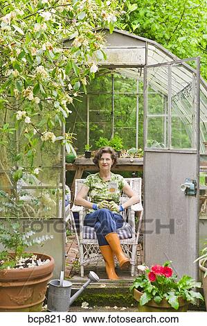 Woman sitting in backyard greenhouse View Large Photo Image Stock Image - Woman sitting in backyard greenhouse. Fotosearch