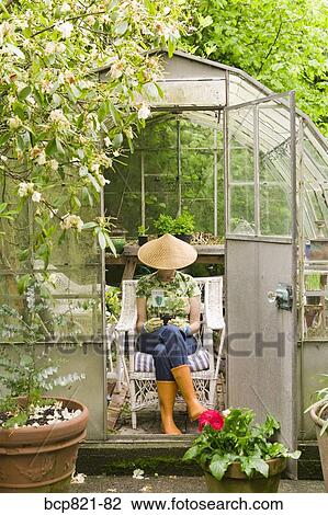 Woman sitting in backyard greenhouse View Large Photo Image Stock Image - Woman sitting in backyard greenhouse. Fotosearch