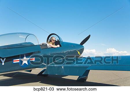 Stock Image - Woman sitting in vintage airplane. Fotosearch