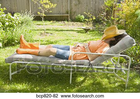Woman sleeping on lounge chair in backyard garden View Large Photo Image Stock Image - Woman sleeping on lounge chair in backyard garden. Fotosearch