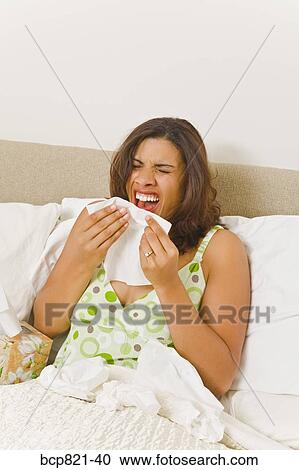 Woman sneezing in bed View Large Photo Image Stock Image - Woman sneezing in bed. Fotosearch