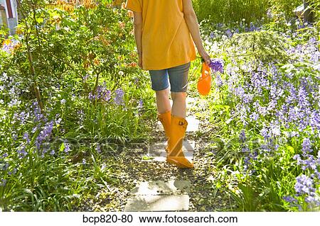 Woman walking through flowered path in garden View Large Photo Image Stock Image - Woman walking through flowered path in garden. Fotosearch