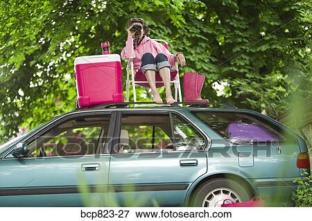 Woman with binoculars picnicking on top of car View Large Photo Image Stock Photo - Woman with binoculars picnicking on top of car. Fotosearch