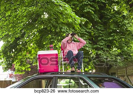 Woman with binoculars picnicking on top of car View Large Photo Image Stock Photograph - Woman with binoculars picnicking on top of car. Fotosearch