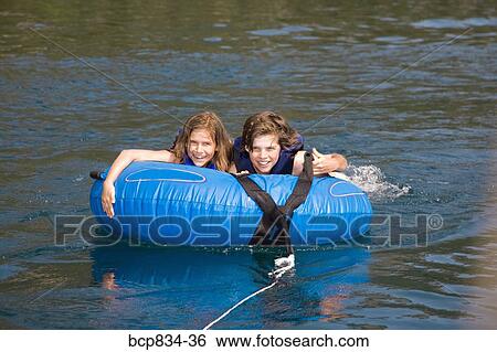 Boy on an inflatable ring with his sister in a lake View Large Photo Image Stock Photograph - Boy on an inflatable ring with his sister in a lake. Fotosearch