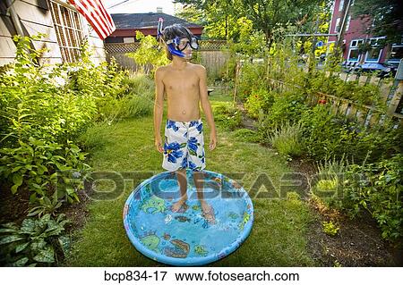 Stock Photo - Boy wearing snorkel and standing in a wading pool. Fotosearch
