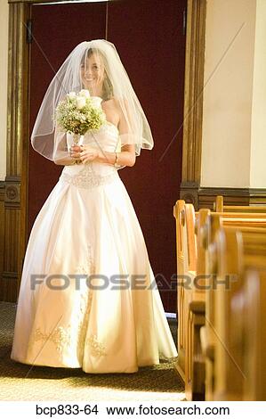 Picture - Bride holding a bouquet of flowers in a church, East Meredith, New York State, USA. Fotosearch