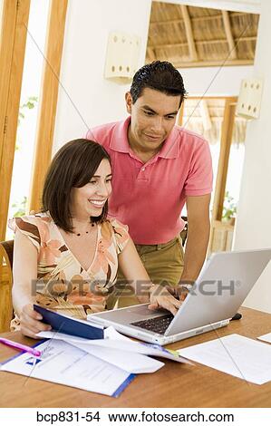 Couple online shopping with a laptop View Large Photo Image Picture - Couple online shopping with a laptop. Fotosearch