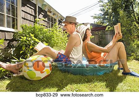 Couple reading books in a wading pool View Large Photo Image Stock Photo - Couple reading books in a wading pool. Fotosearch