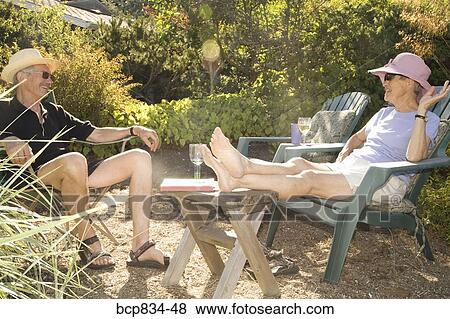 Couple sitting on adirondack chairs View Large Photo Image Stock Photo - Couple sitting on adirondack chairs. Fotosearch