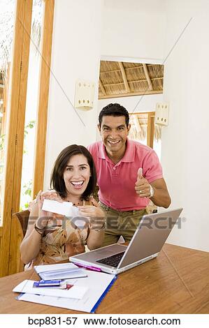 Couple smiling in front of a laptop View Large Photo Image Stock Photo - Couple smiling in front of a laptop. Fotosearch