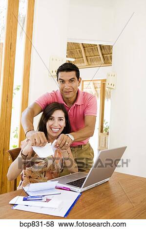 Couple tearing a paper in front of a laptop View Large Photo Image Stock Photo - Couple tearing a paper in front of a laptop. Fotosearch