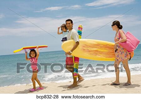 Stock Photo - Couple with their children walking on the beach. Fotosearch