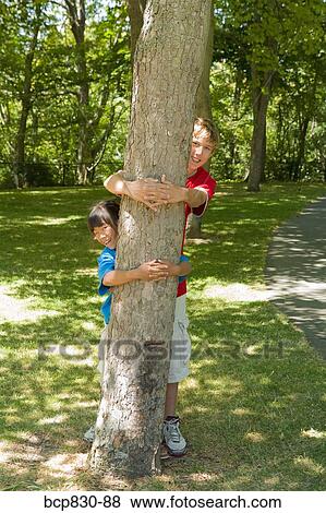 Friends hugging a tree in a garden View Large Photo Image Stock Photo - Friends hugging a tree in a garden. Fotosearch