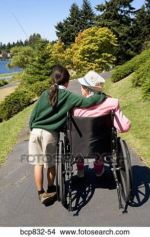 Girl assisting a disabled woman in a wheelchair View Large Photo Image Picture - Girl assisting a disabled woman in a wheelchair. Fotosearch