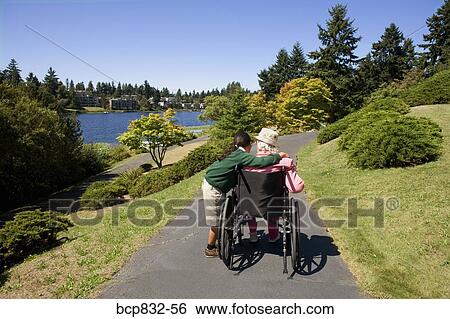 Girl assisting a disabled woman in a wheelchair View Large Photo Image Stock Photograph - Girl assisting a disabled woman in a wheelchair. Fotosearch