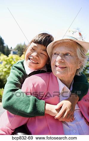 Girl hugging her grandmother in a garden View Large Photo Image Stock Photo - Girl hugging her grandmother in a garden. Fotosearch