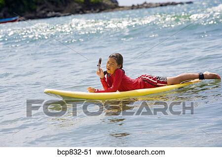 Girl lying on a surfboard and using a mobile phone View Large Photo Image Stock Image - Girl lying on a surfboard and using a mobile phone. Fotosearch