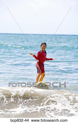 Girl surfing in the sea and holding a mobile phone View Large Photo Image Picture - Girl surfing in the sea and holding a mobile phone. Fotosearch