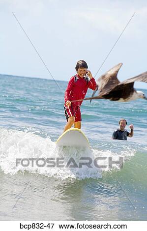 Girl surfing in the sea and talking on a mobile phone View Large Photo Image Stock Photo - Girl surfing in the sea and talking on a mobile phone. Fotosearch