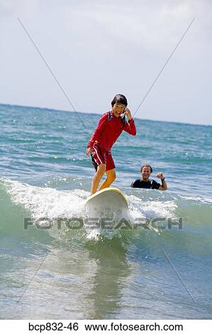 Girl surfing in the sea and talking on a mobile phone View Large Photo Image Stock Photograph - Girl surfing in the sea and talking on a mobile phone. Fotosearch