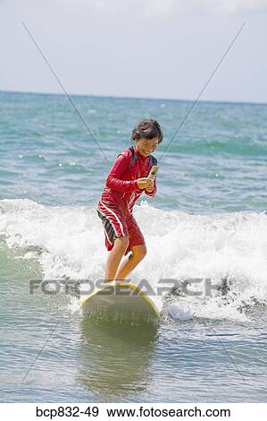 Girl surfing in the sea and using a mobile phone View Large Photo Image Stock Photo - Girl surfing in the sea and using a mobile phone. Fotosearch