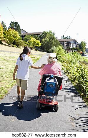 Girl walking with her grandmother sitting in a wheelchair View Large Photo Image Stock Photo - Girl walking with her grandmother sitting in a wheelchair. Fotosearch