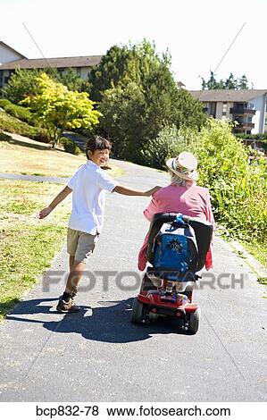 Girl walking with her grandmother sitting in a wheelchair View Large Photo Image Stock Photo - Girl walking with her grandmother sitting in a wheelchair. Fotosearch