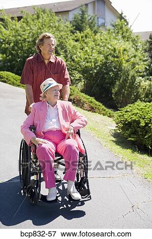 Man assisting his disabled mother in a wheelchair View Large Photo Image Stock Photo - Man assisting his disabled mother in a wheelchair. Fotosearch