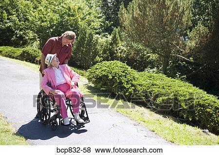 Man assisting his disabled mother in a wheelchair View Large Photo Image Stock Photo - Man assisting his disabled mother in a wheelchair. Fotosearch